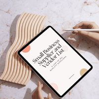 A digital PDF list titled 'Small Business Supplier and Vendor List' displayed on a tablet, held by a person with a stylus, against a marble background with a wooden decorative item.