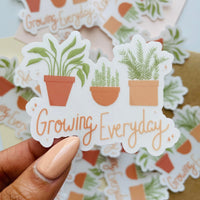 growing everyday potted plants clear sticker. 3 potted plants lined up with the phrase "growing everyday" below it written in hand lettered font