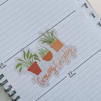 growing everyday potted plants clear sticker. 3 potted plants lined up with the phrase "growing everyday" below it written in hand lettered font