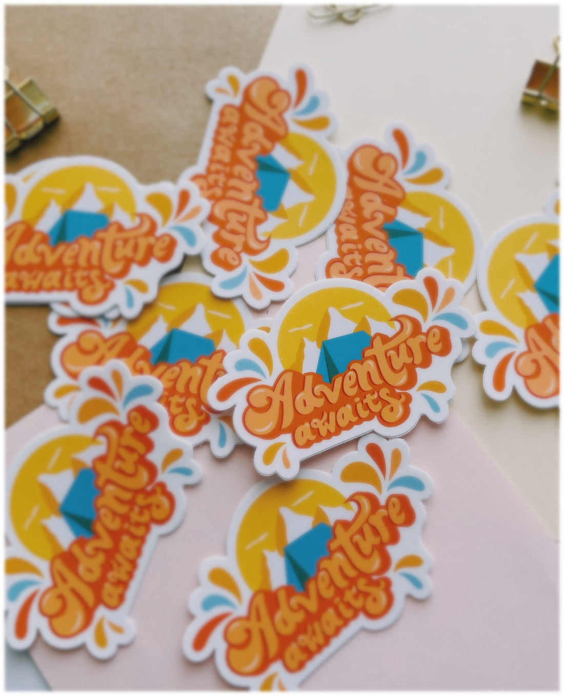 Orange and blue camping sticker that says Adventure Awaits. Includes a mountain range and camping tent