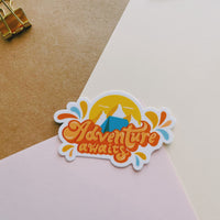 Orange and blue camping sticker that says Adventure Awaits. Includes a mountain range and camping tent