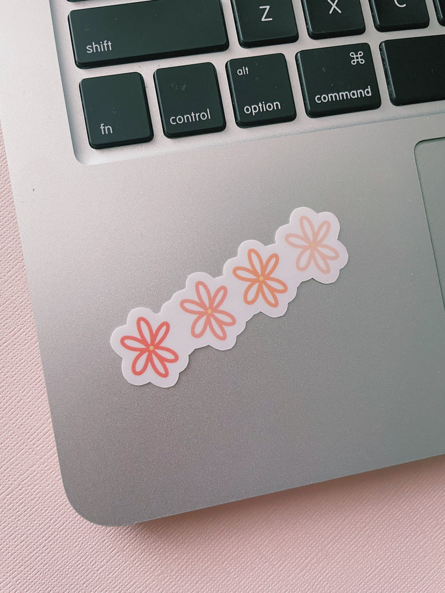 4 pink flowers vinyl sticker, that change in shade. Starting with the darkest on the left and lightest on the right. Sticker is on Macbook near keyboard