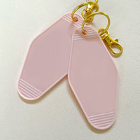 two blank hotel keychains in light pink. Both with gold keyring and lobster clasp