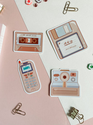 90s nostalgia collection full sticker pack, 4 fun stickers. A mixtape, floppy disk, zokia cell phone, and a polaroid camera that is all 90s themed